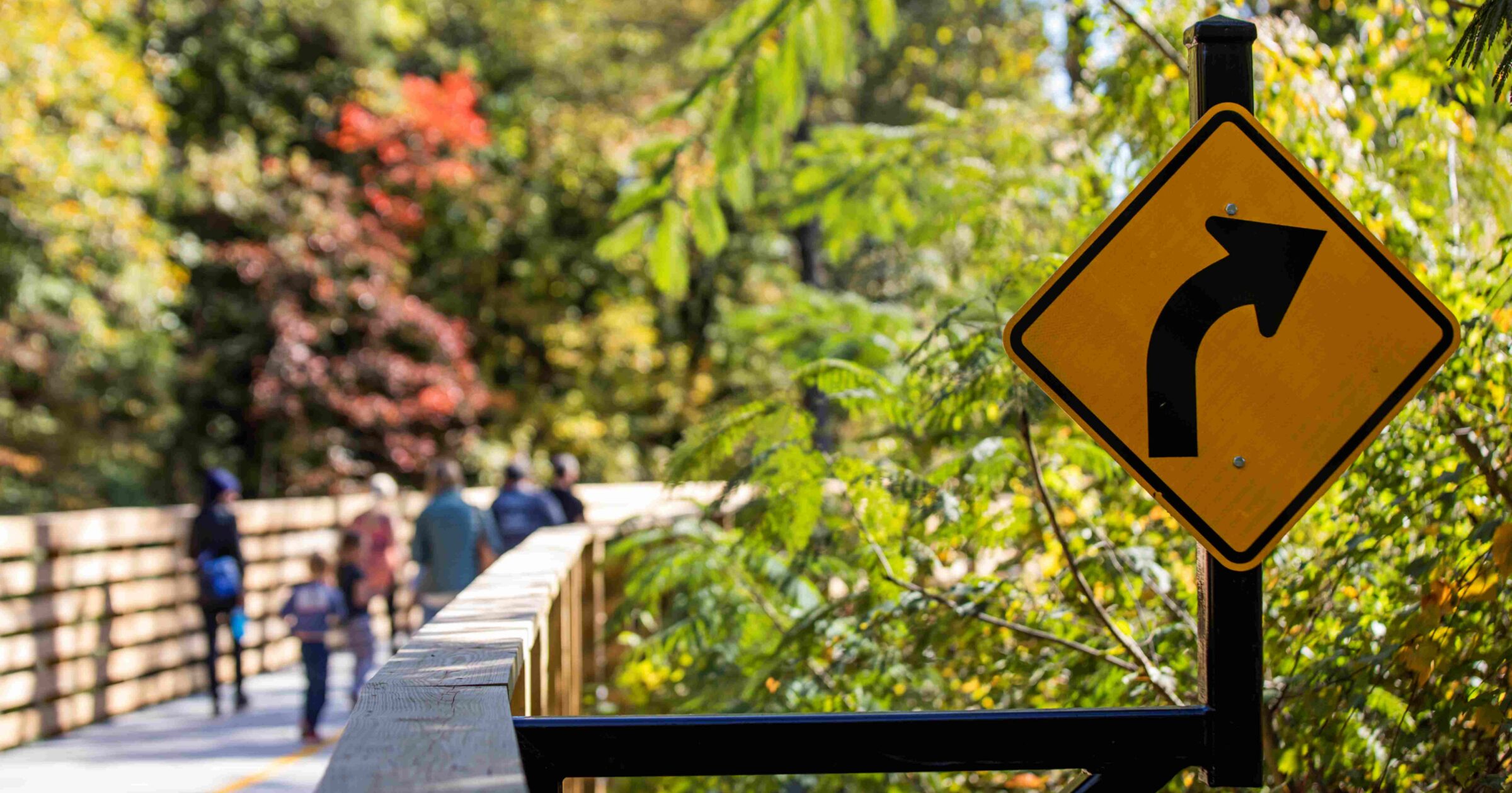 People walking on the Bob Callan trail with close-up of a sign indicating a right turn
