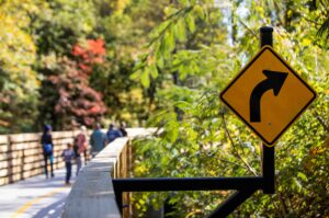 People walking on the Bob Callan trail with close-up of a sign indicating a right turn