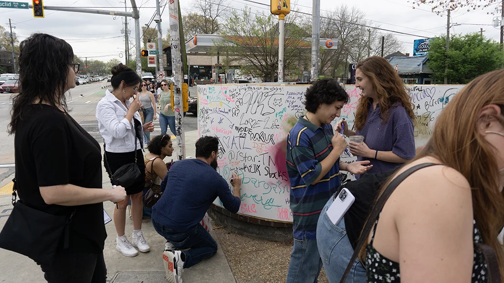 People writing messages on a wall in Little 5 Points