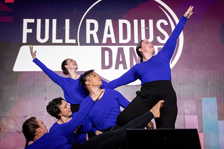 Four dancers with their arms out stretched
