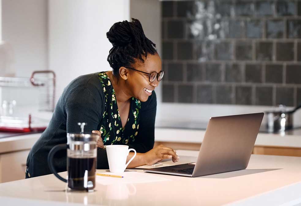 A woman teleworks while drinking coffee.