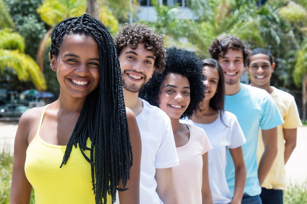 Beautiful african american woman with dreadlocks with multi ethnic friends in line outdoor in the summer