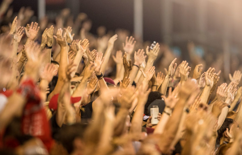 Passionate fans cheer and raise hands at a sporting event