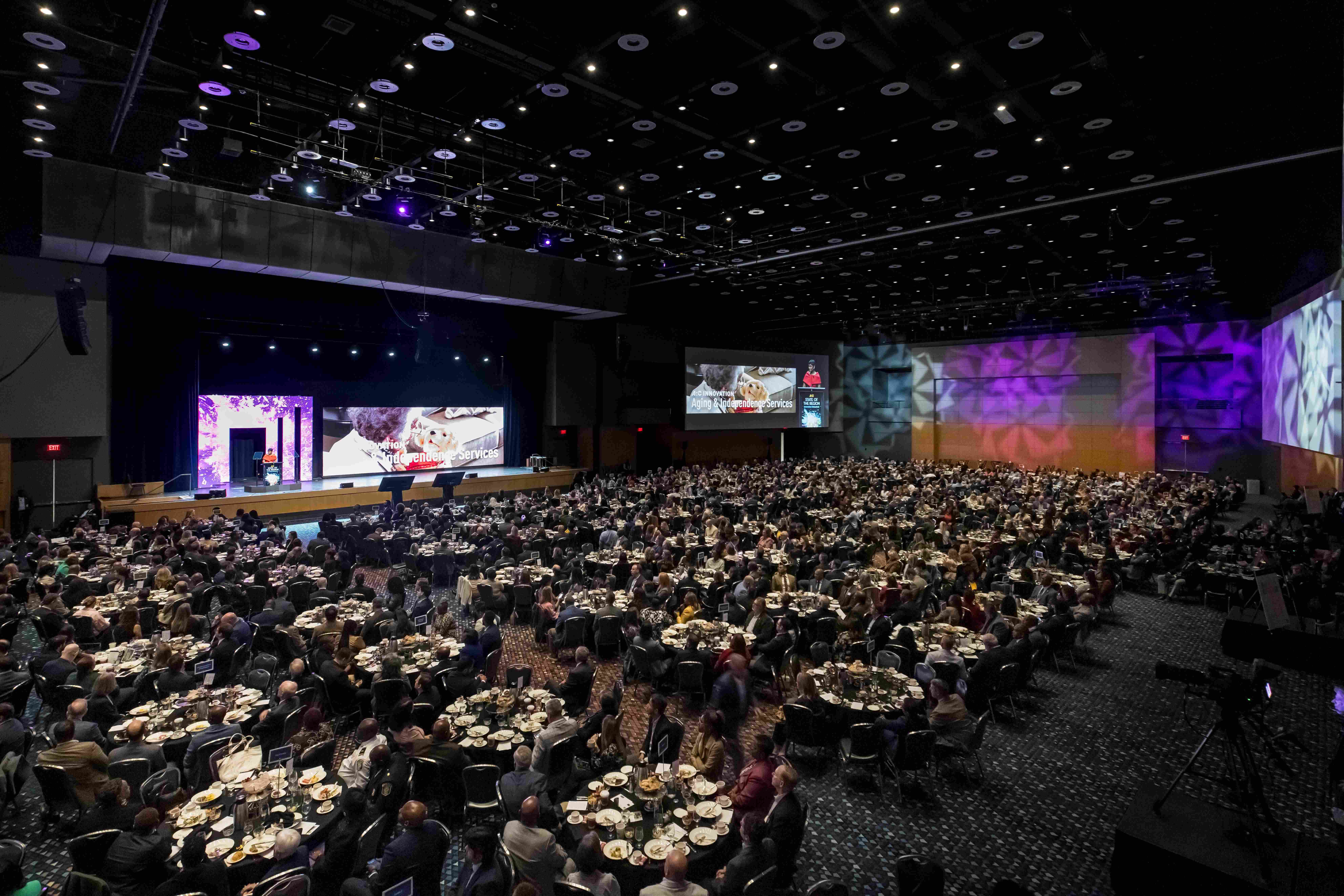 View of the State of the Region event from above, showing rows of tables and the stage