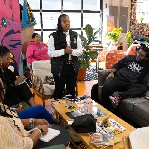A person presenting to a group of people in a casual setting.